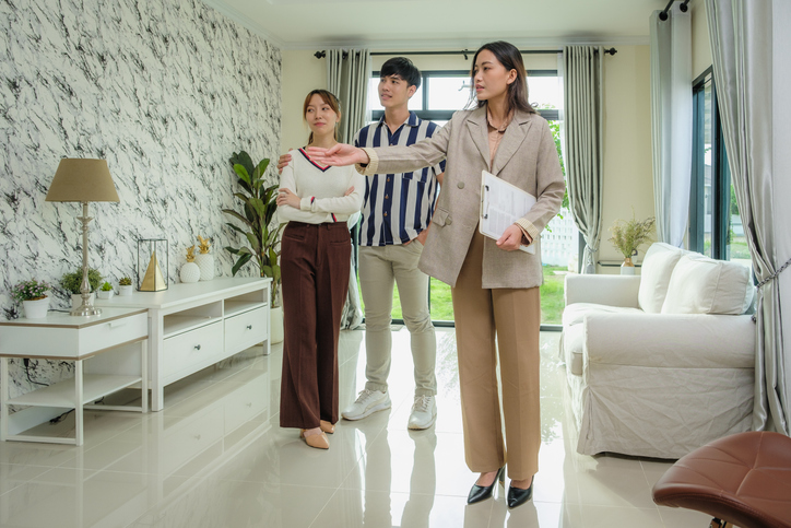 A couple visits the apartment to ask the real estate agent if what is the best month to rent an apartment.