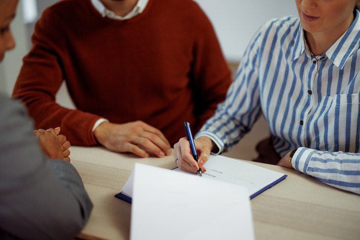 Two people reviewing and signing lease documents with a property manager – fall lease renewal tips for landlords.