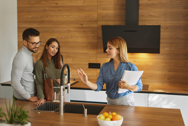 A property manager showing a modern apartment kitchen to a couple, highlighting the personalized nature of residential vs commercial property management.