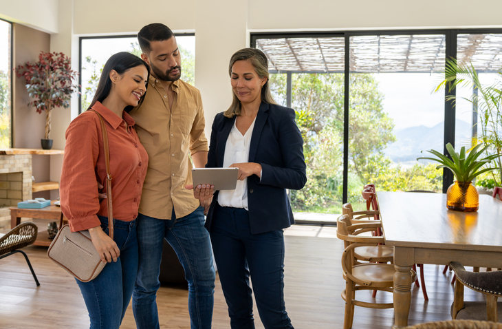 Property management vs realtor discussion, property management professional reviewing rental property details with prospective tenants inside modern managed home.