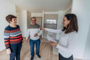 Property manager handing keys to new tenants inside a rental property while discussing the role of a leasing agent vs property manager.