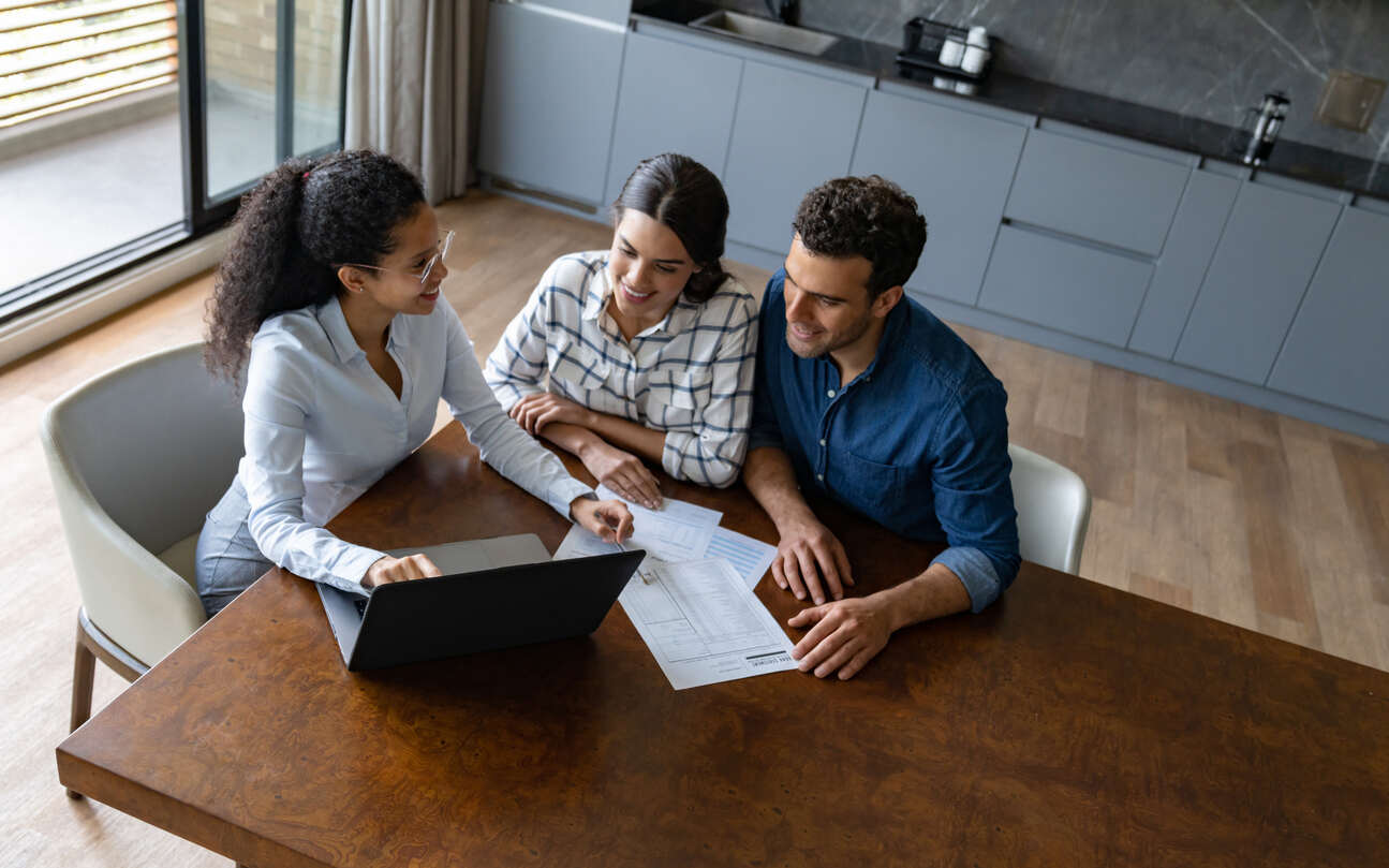 Property manager reviewing documents with clients discussing who regulates property management companies and professional management requirements.